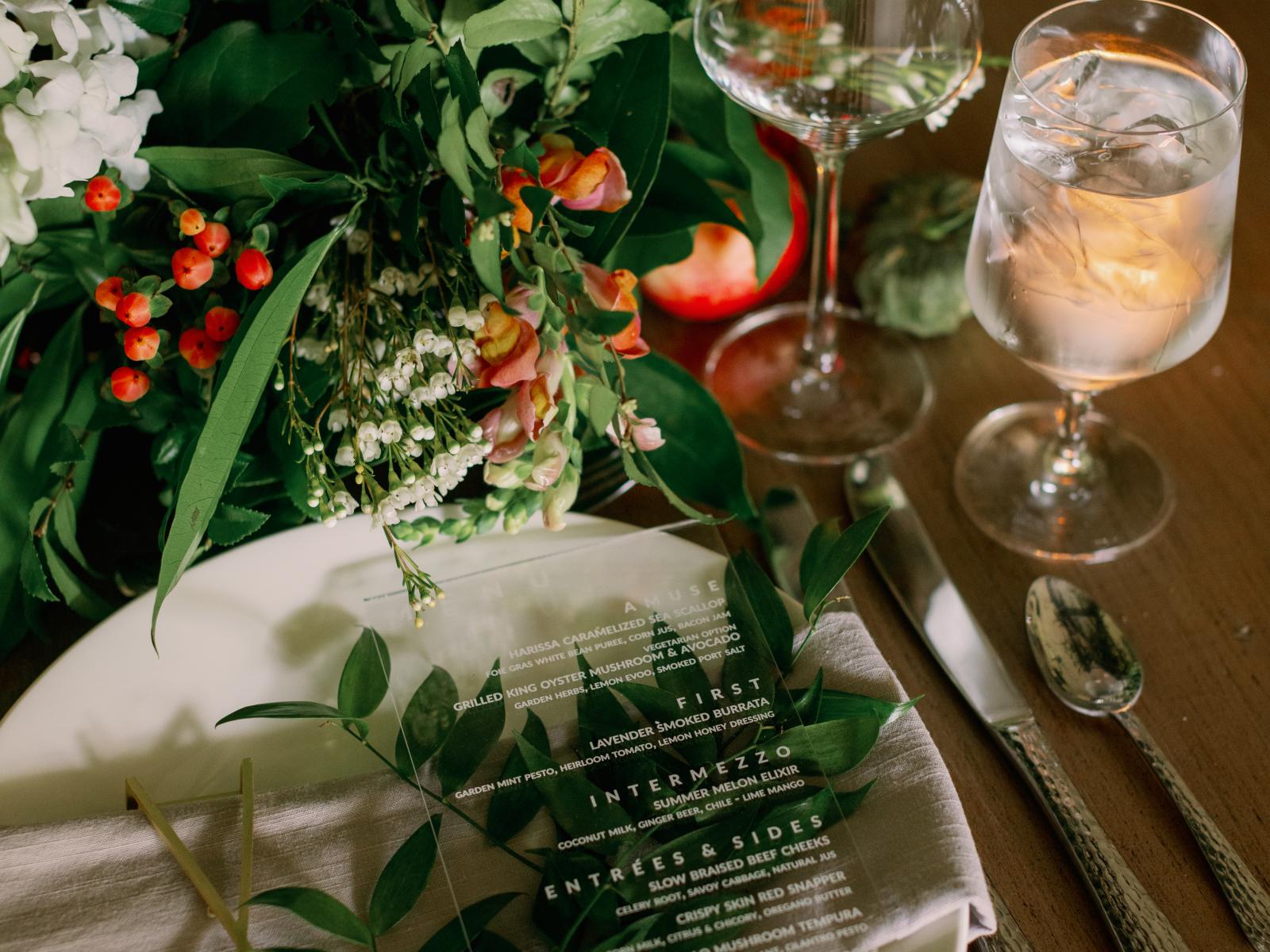 Wedding table decoration. A circular white plate next to silverware and two different wine glasses.