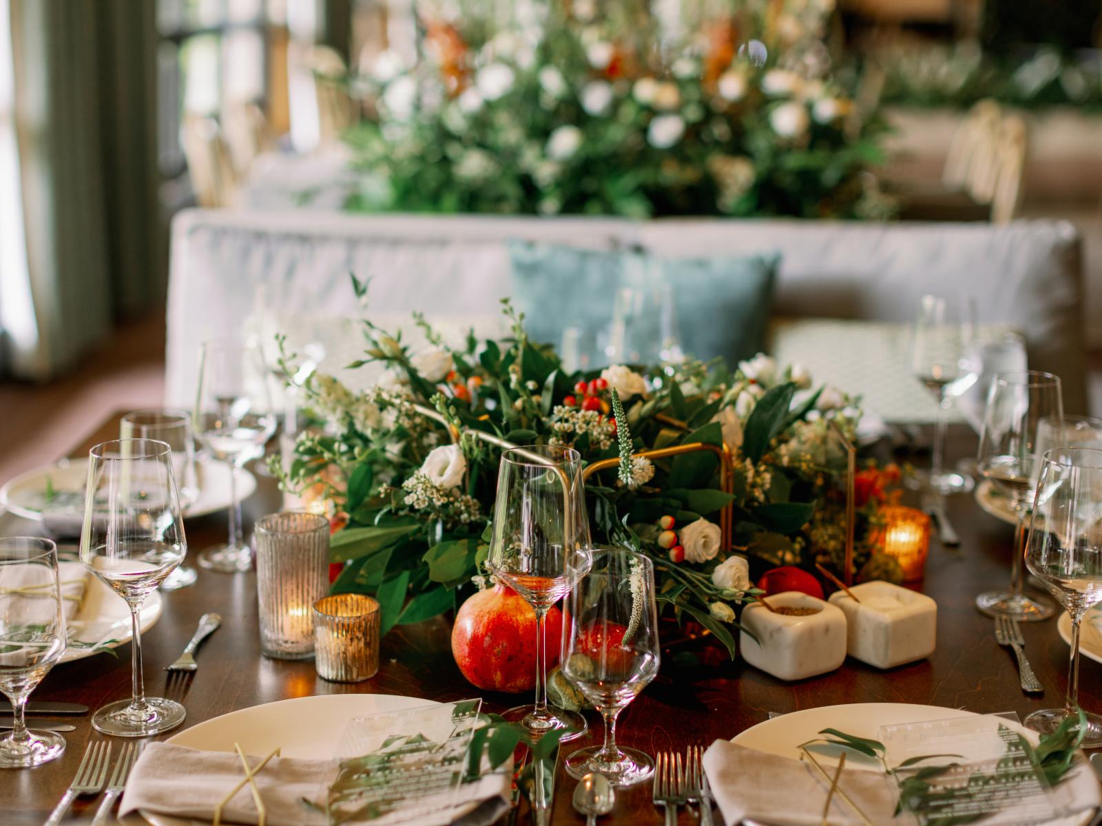 Wedding table decoration. Centered plant decoration surrounded by plates, silverware, and two wine glasses per sit.